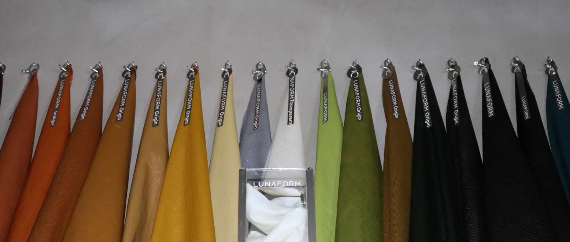 A row of LUNAFORM™ sheets in the full colour range, hanging under the LUNAFORM sign